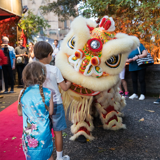 Chinese Lion being fed by two children